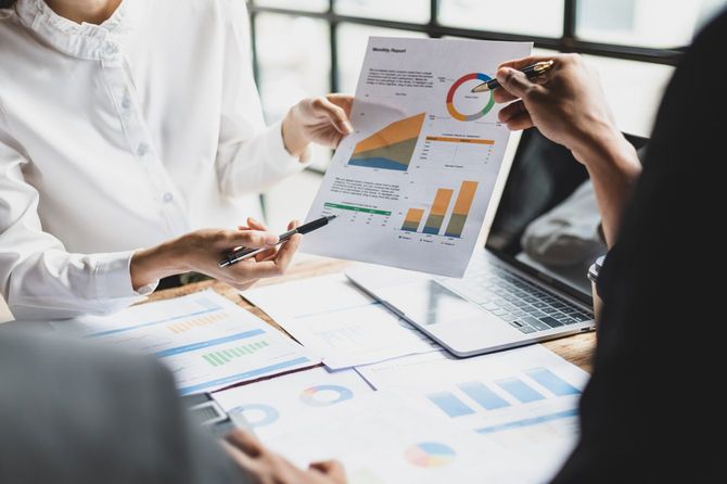 グラフの描かれた資料を使って会話するビジネスパーソン