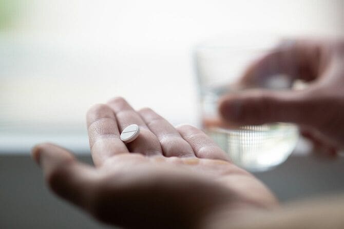 錠剤とコップ一杯の水を持つ手