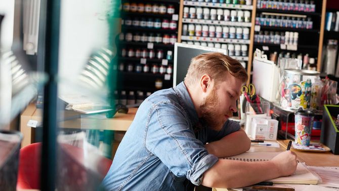 スケッチブックに何かを書き込むひげ面の男性