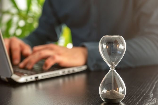職場での時間的プレッシャーの象徴としてオフィスで時間がなくなる砂時計