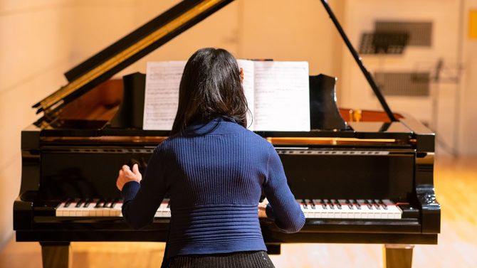コンサートホールでピアノを弾く女性