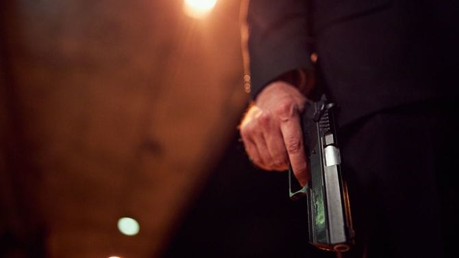 夜道で拳銃を所持する男性の手元