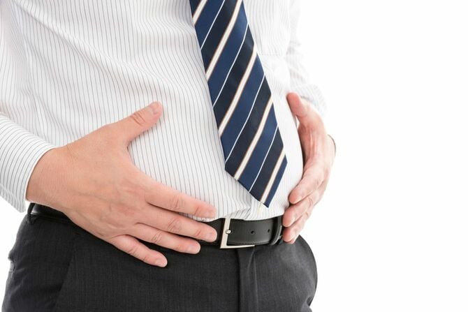 自身の太ったお腹を触るビジネスマン