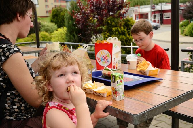 マクドナルドでランチする家族。ハッピーセットを食べている子供