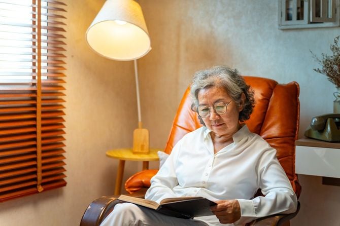 ソファーに座り、読書しているシニア女性