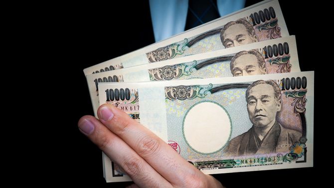 札束を指に挟んで提示する男性の手元