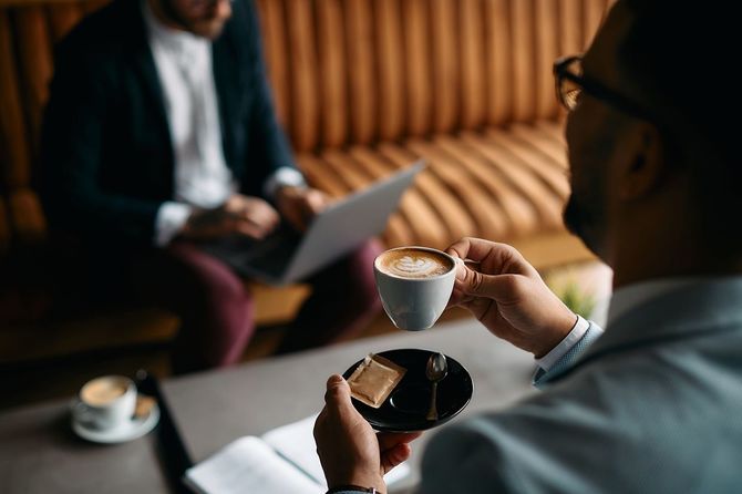 カフェで同僚とコーヒーを飲むビジネスマン