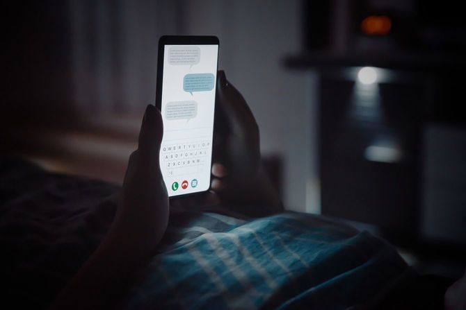 寝る前にベッドに横になりスマホを見ている人