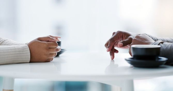テーブルに向かい合って座る男女の手