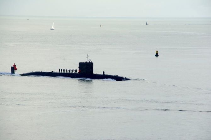 潜水艦が水面に顔を出し、乗組員がセイルに立っている