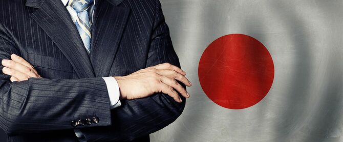 日本の国旗の背景で腕を組む男性
