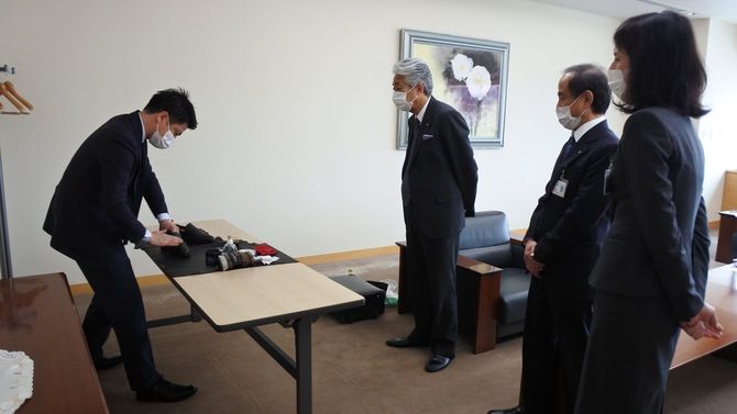 会長室で山口会長（中央）の靴磨きをする濱岡さん（左）