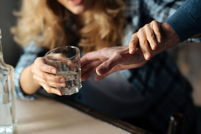 お酒が入ったグラスを取ろうとする男性を止める女性