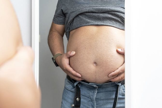 鏡の前でお腹を気にしている男性