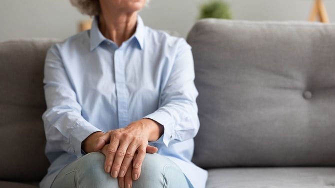 あまり幸せそうではない年配の女性がソファに座っている