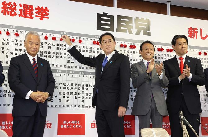 当選確実の候補者名に花を付ける岸田文雄首相（左から2人目、自民党総裁）。左端は甘利明幹事長＝2021年10月31日、東京都千代田区