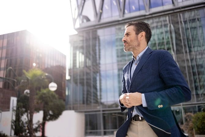 オフィスビルの前に立つ自信を持った中年のビジネスマン