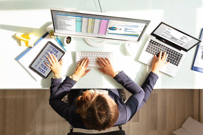 電子機器でマルチタスク作業を行うビジネスウーマンのオーバーヘッドビュー