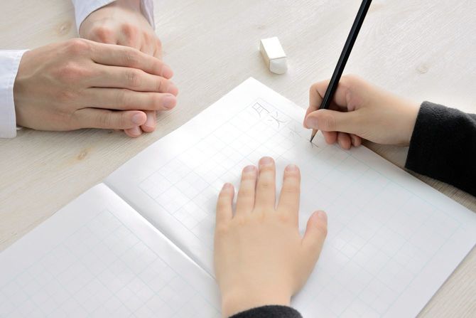 子供が漢字ドリルの宿題をするのを見守る母親