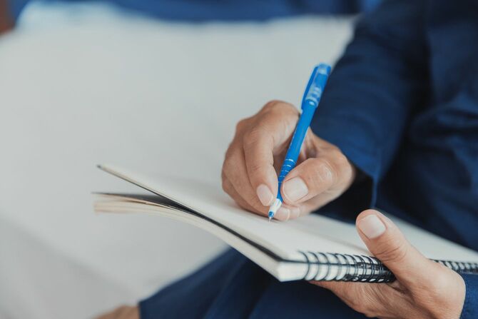 メモ帳に文字を書いている男性の手元