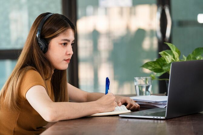 学生は、ワイヤレスヘッドフォンを着用し、言語オンラインウォッチを勉強