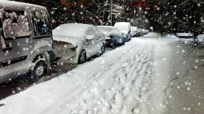 雪の夜に道路に駐車した車の列