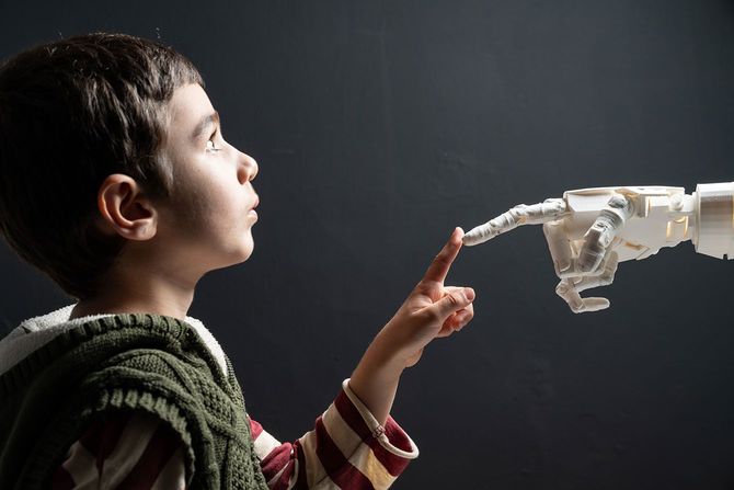 ヒューマノイドロボットの指先と、人差し指を合わせる男の子