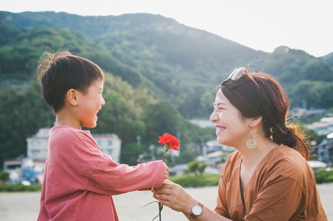 母親にカーネーションの花を手渡す少年