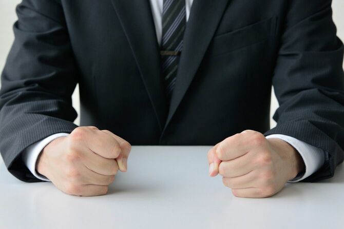 机に握りこぶしを置いたビジネスマン