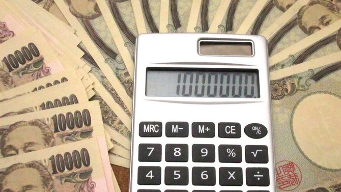 大量の一万円札の上に置かれた電卓の表示には100万