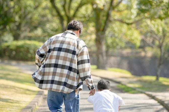 男の子が父親と手をつないで歩く