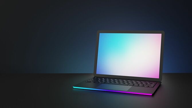 暗い背景に青いピンクの照明と空白の画面の場所とラップトップコンピュータ