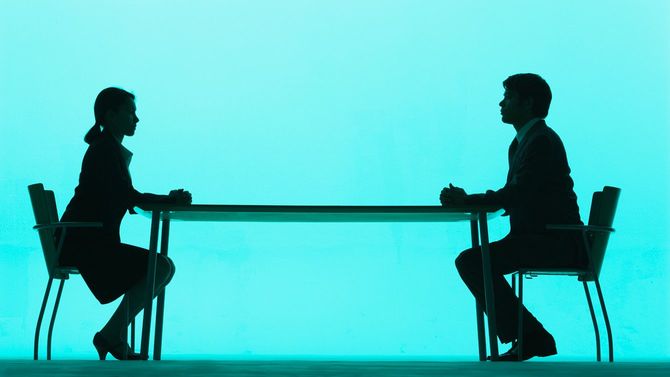 向かい合って着席し、話し合う男女