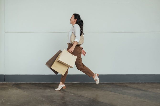 ショッピングバッグを手に楽しそうに走る女性