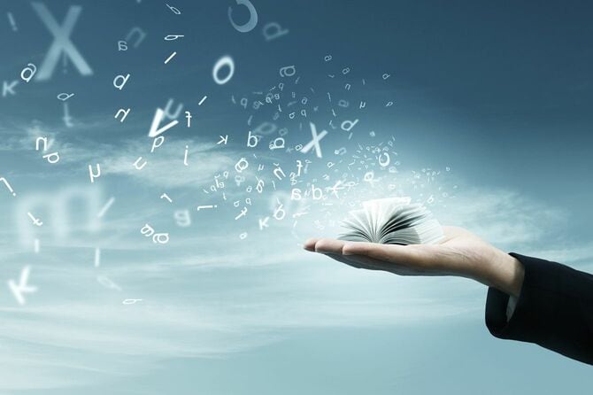 掌に載せた本からこぼれ出た言葉が空を舞っている