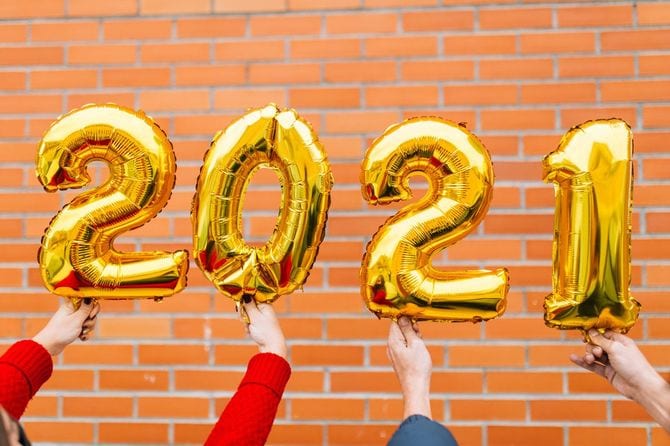 金色の2021の数字型バルーンを持つ男女の手