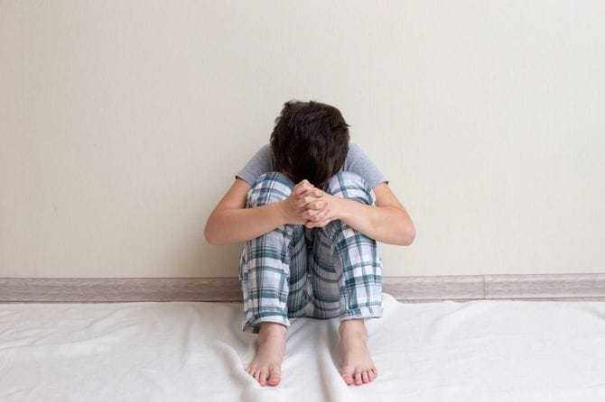 床に座って悲しむ少年