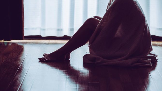 薄暗い部屋に座り込む孤独な女性