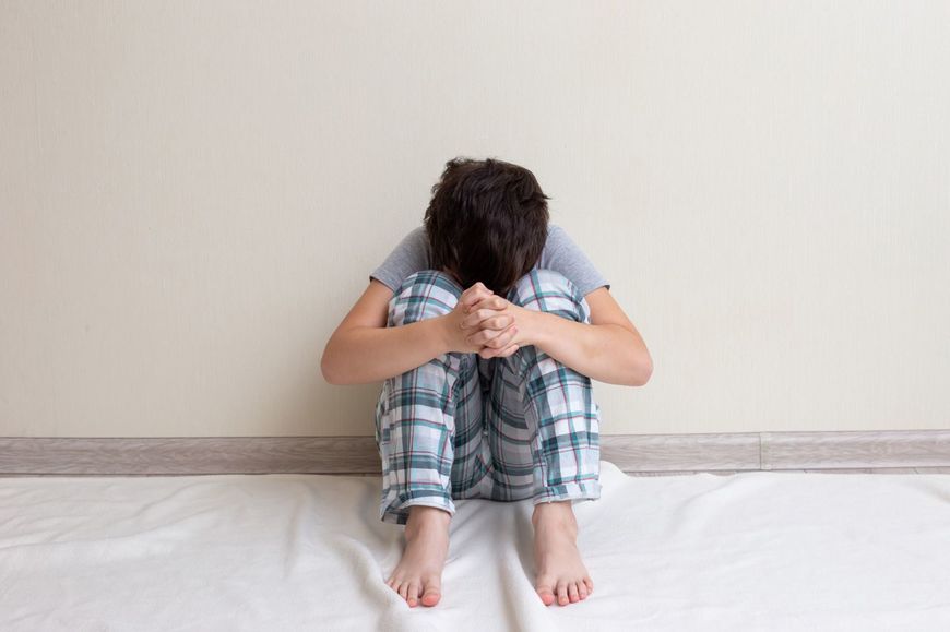 床に座って悲しむ少年