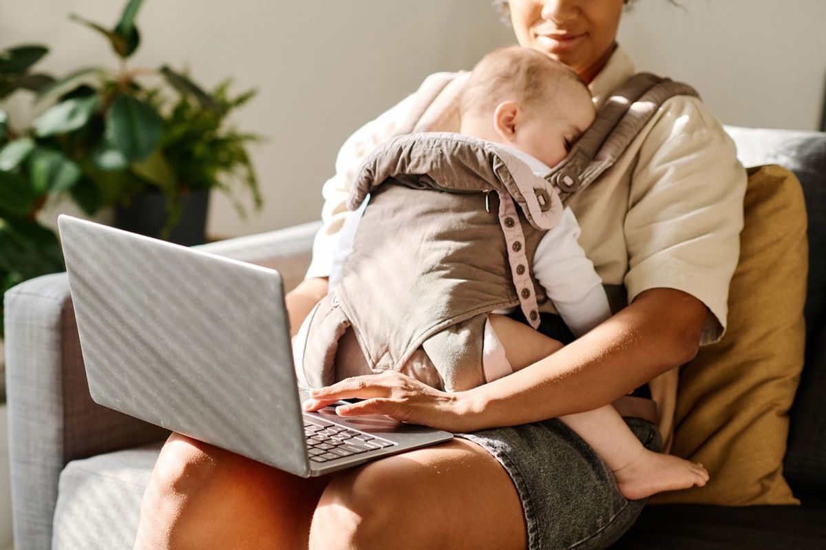 赤ちゃんを抱っこしながらノートパソコンで作業する女性
