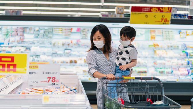 子供と一緒にマスクを着用し、スーパーで買い物する女性