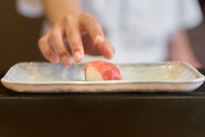 お皿に寿司をのせる料理人