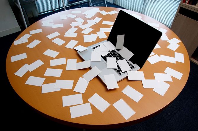 テーブルの上に乱雑な空白のカードとラップトップ。