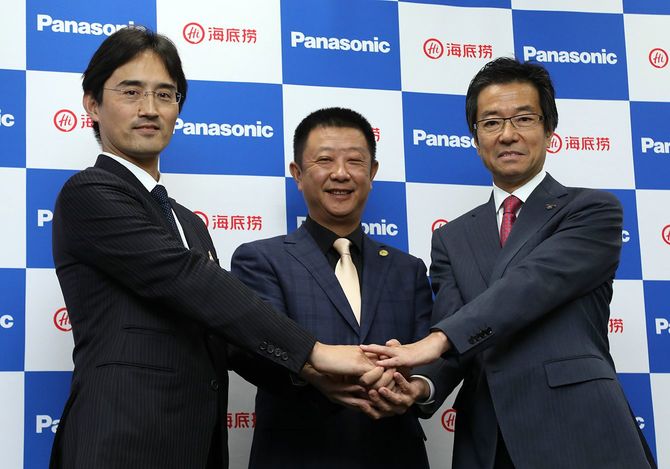 「スマートレストラン」事業について記者会見し、握手する（右から）パナソニックの樋口泰行専務、海底撈インターナショナルホールディングスの張勇董事長、北京瀛海スマート自動化科学技術有限公司の総経理の山下純氏＝2018年10月25日、東京都中央区