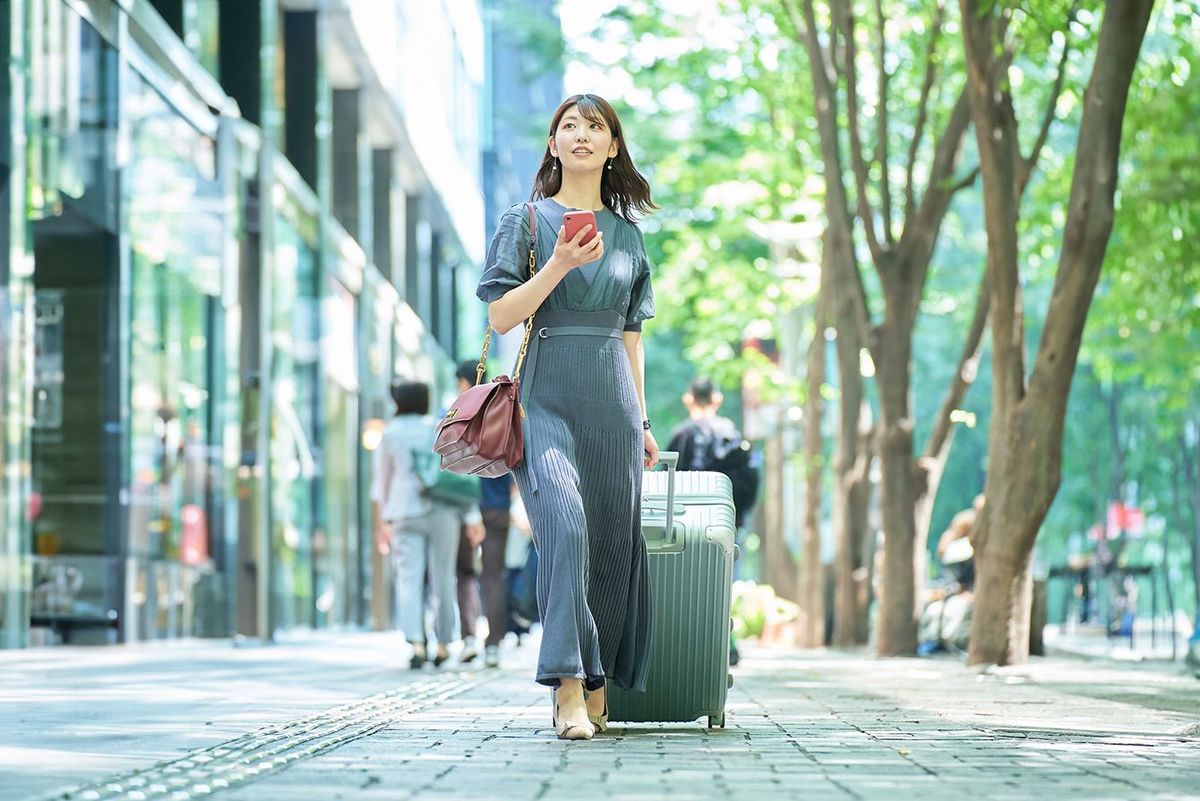 スーツケースを持って街を歩く女性