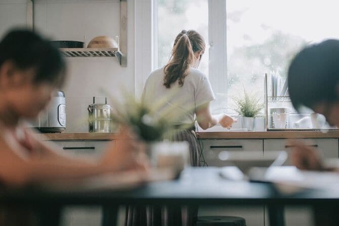 母親が皿を洗っている間ダイニングルームで勉強している子供たち