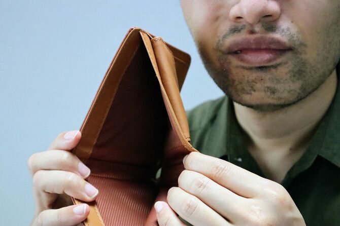 空の財布を広げている男性