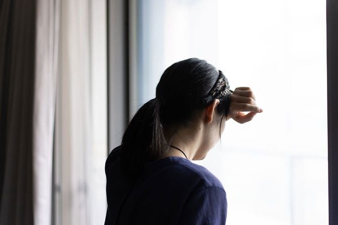 窓ガラスに顔を押し付けて嘆く女性