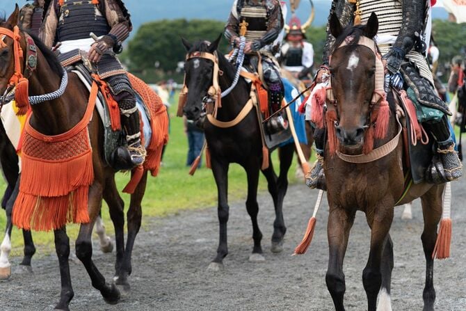 武士の甲冑を身にまとって馬に乗る人々