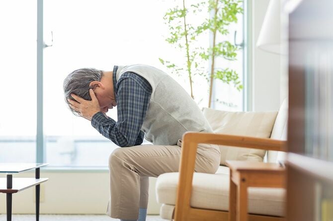 頭を抱えるシニア男性
